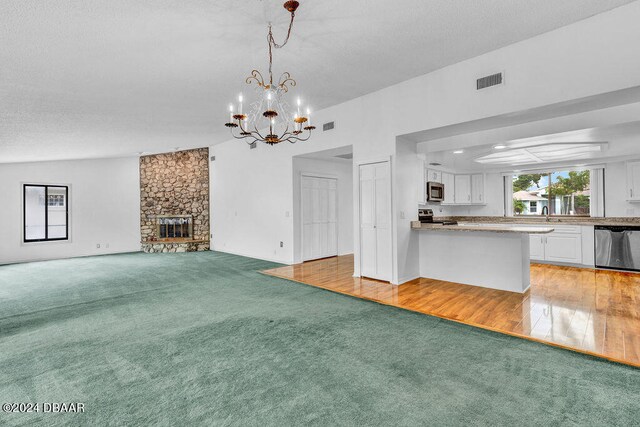 unfurnished living room featuring a fireplace, a notable chandelier, sink, light hardwood / wood-style floors, and lofted ceiling