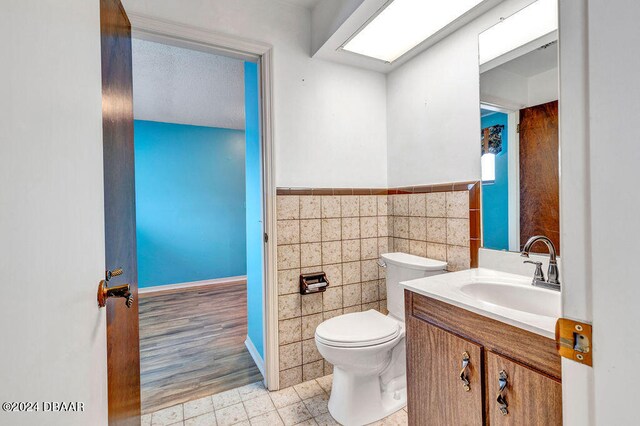 bathroom with hardwood / wood-style flooring, vanity, toilet, and tile walls