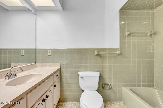 bathroom featuring toilet, tile walls, tile patterned flooring, vanity, and a bath