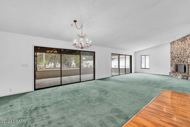 unfurnished living room featuring a fireplace, a notable chandelier, a healthy amount of sunlight, and carpet floors