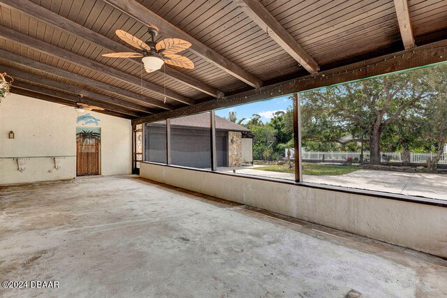 unfurnished sunroom with beamed ceiling and ceiling fan