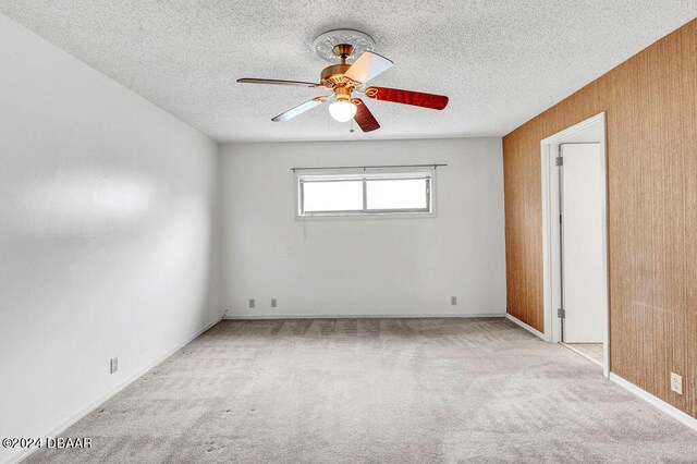 spare room with ceiling fan, wooden walls, and a textured ceiling