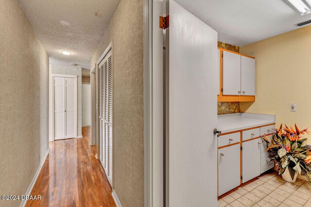 hall featuring light hardwood / wood-style flooring and a textured ceiling