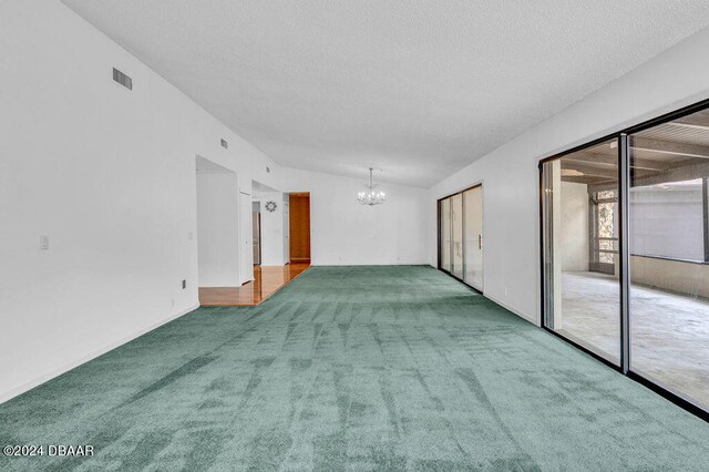 carpeted spare room with a chandelier, a textured ceiling, and lofted ceiling