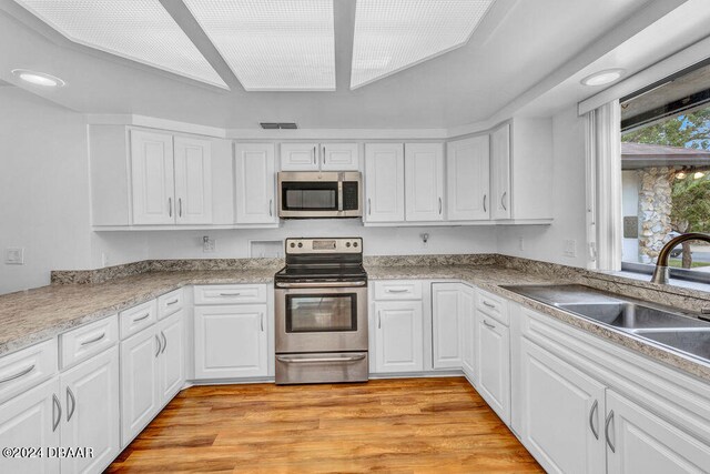 kitchen featuring white cabinetry, appliances with stainless steel finishes, sink, and light hardwood / wood-style flooring