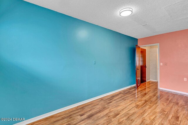 unfurnished room featuring light wood-type flooring and a textured ceiling