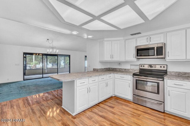 kitchen featuring white cabinets, kitchen peninsula, appliances with stainless steel finishes, and lofted ceiling