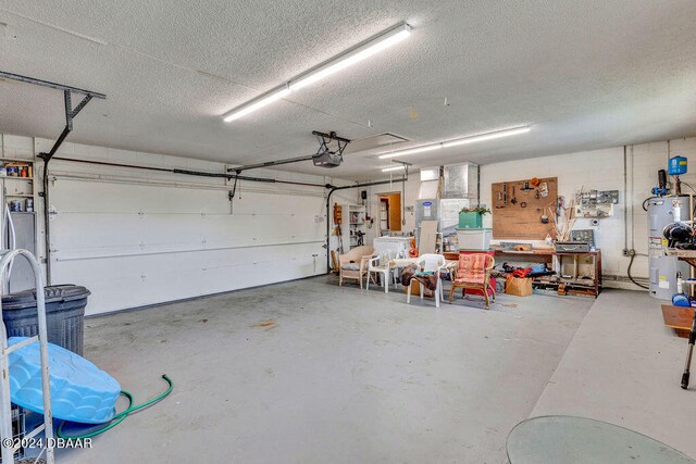 garage with a garage door opener, a workshop area, and electric water heater