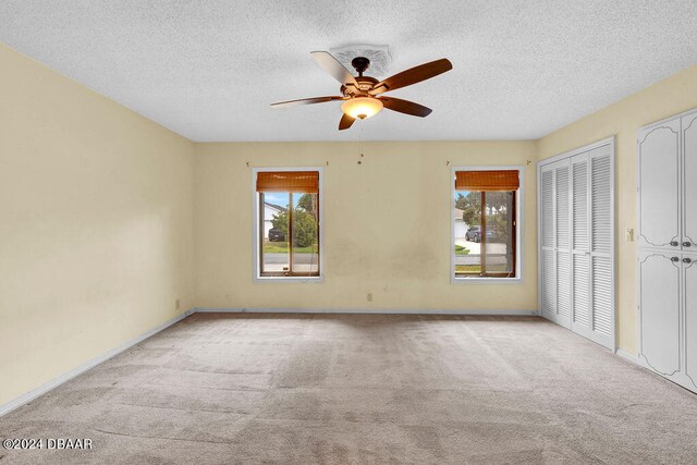 carpeted empty room featuring a textured ceiling and ceiling fan