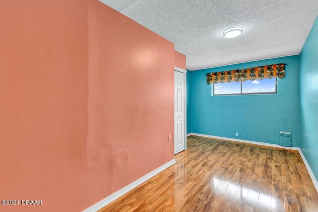 unfurnished room with wood-type flooring and a textured ceiling