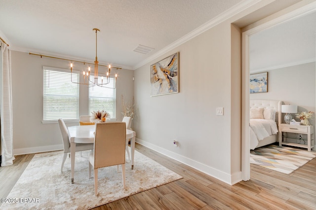 dining space with light wood-style flooring, visible vents, ornamental molding, and a chandelier