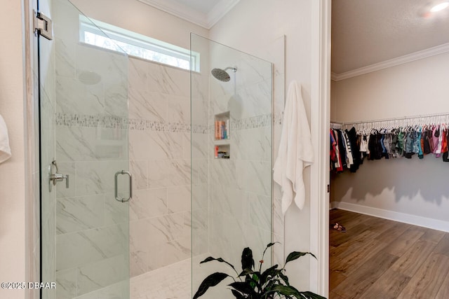 full bath featuring wood finished floors, baseboards, a spacious closet, ornamental molding, and a stall shower