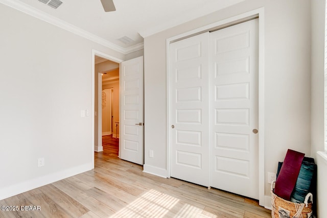 unfurnished bedroom with ornamental molding, light wood-type flooring, a closet, and baseboards