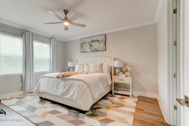 bedroom featuring ornamental molding, light wood-style flooring, baseboards, and a ceiling fan