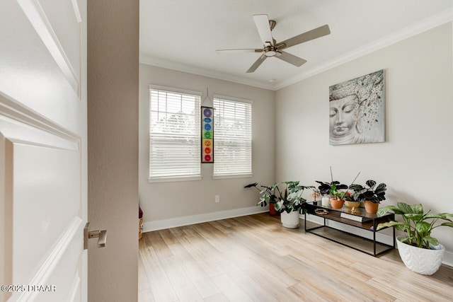 living area featuring a ceiling fan, crown molding, baseboards, and wood finished floors