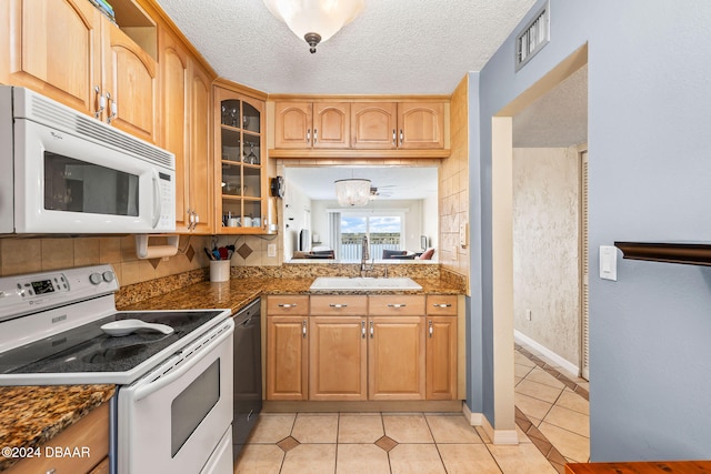 kitchen with a textured ceiling, sink, light tile patterned flooring, and white appliances