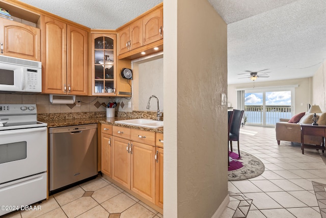 kitchen featuring ceiling fan, sink, white appliances, decorative backsplash, and light tile patterned flooring