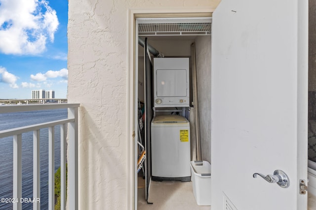 clothes washing area with stacked washer and dryer and a healthy amount of sunlight