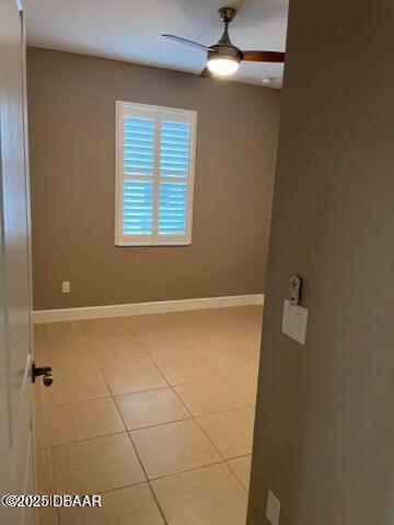 spare room featuring light tile patterned flooring, ceiling fan, and baseboards