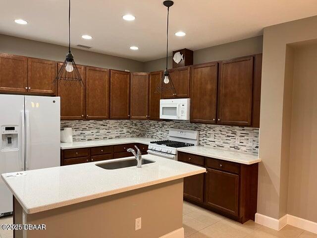 kitchen featuring light countertops, white appliances, a sink, and decorative backsplash