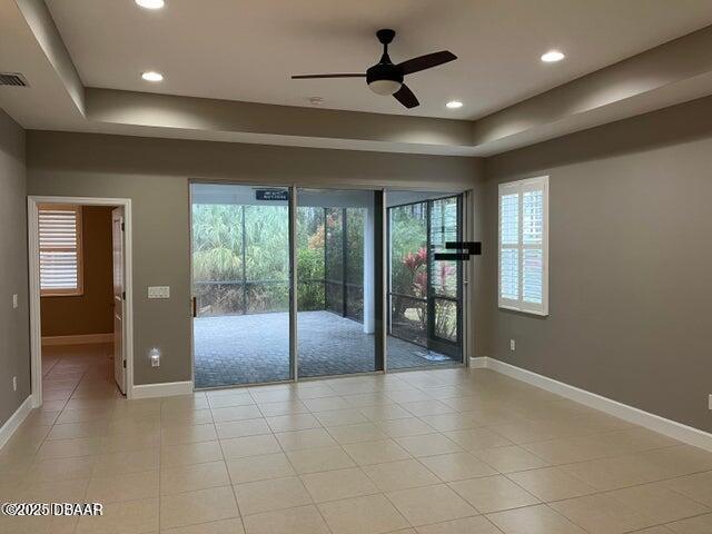 spare room featuring a tray ceiling, ceiling fan, and light tile patterned flooring