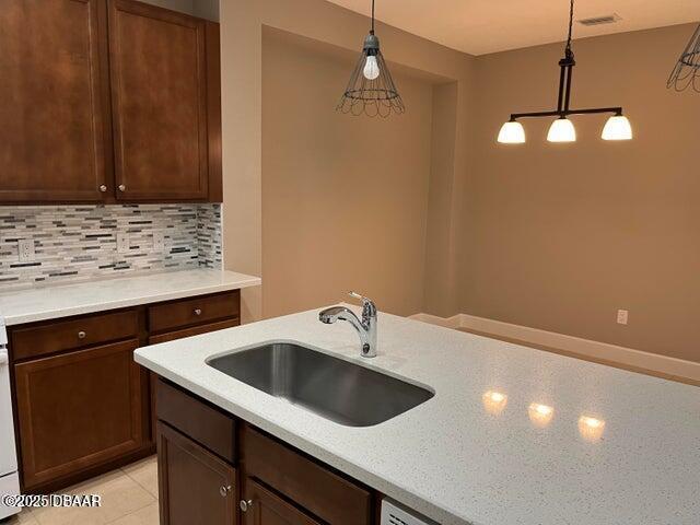 kitchen featuring hanging light fixtures, tasteful backsplash, sink, and light tile patterned floors