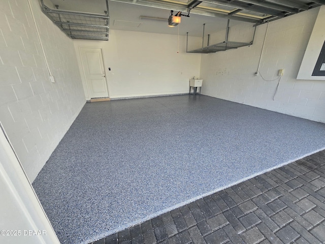 garage featuring concrete block wall, a sink, and a garage door opener