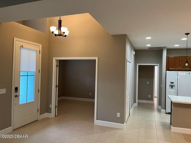 kitchen featuring white refrigerator with ice dispenser, light tile patterned floors, a notable chandelier, and decorative light fixtures