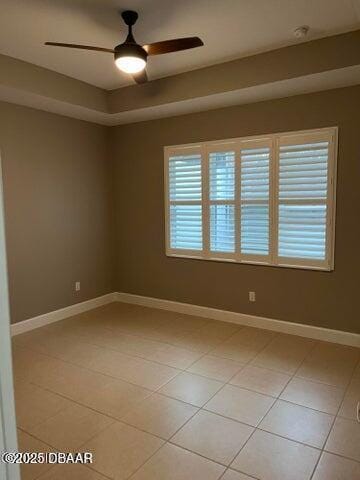 spare room featuring a raised ceiling, ceiling fan, and light tile patterned flooring