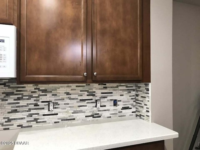 details featuring dark brown cabinetry, light countertops, and backsplash