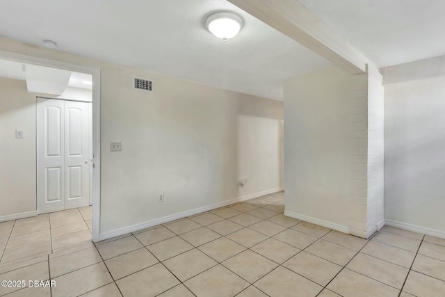 empty room featuring light tile patterned flooring and beamed ceiling