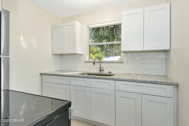 kitchen with white cabinetry, light stone countertops, sink, and tasteful backsplash