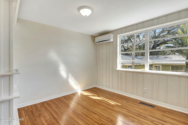 empty room with hardwood / wood-style floors and a wall mounted air conditioner