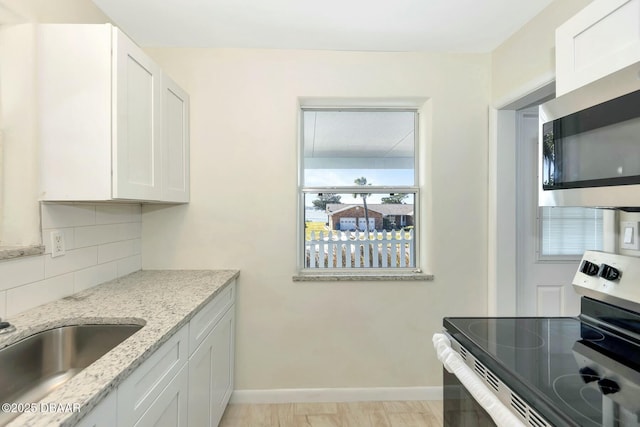 kitchen with white cabinetry, stainless steel appliances, and light stone countertops