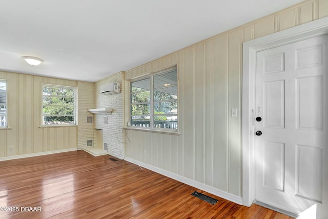 unfurnished living room with wood-type flooring and a wall unit AC