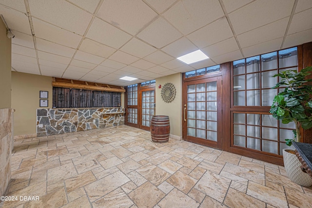 basement with a paneled ceiling and french doors