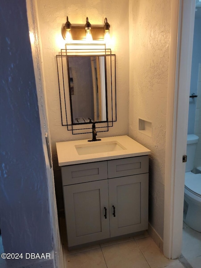 bathroom with tile patterned flooring, vanity, and toilet