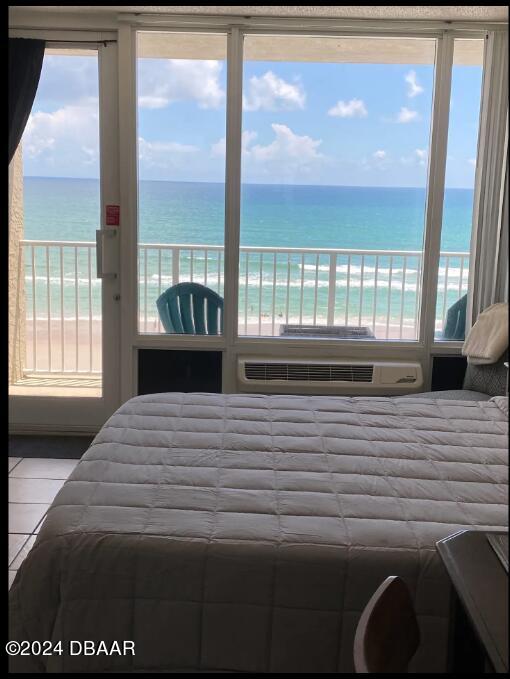 tiled bedroom with a view of the beach and a water view