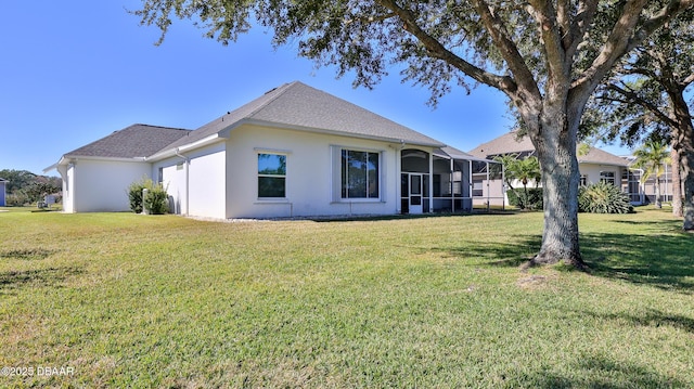 rear view of house featuring a lanai and a lawn