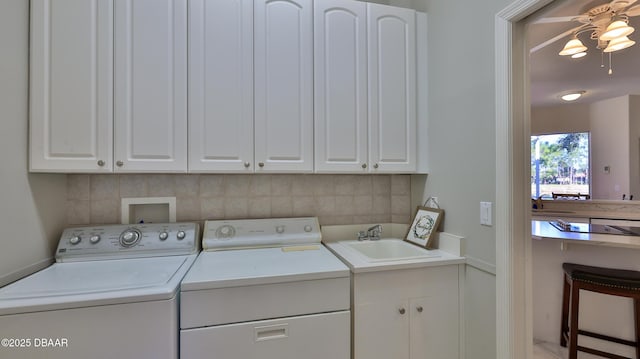 clothes washing area with ceiling fan, washing machine and dryer, sink, and cabinets