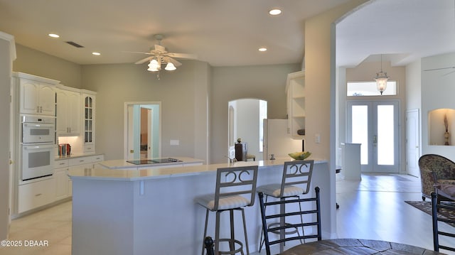 kitchen featuring white appliances, white cabinets, french doors, a kitchen breakfast bar, and kitchen peninsula