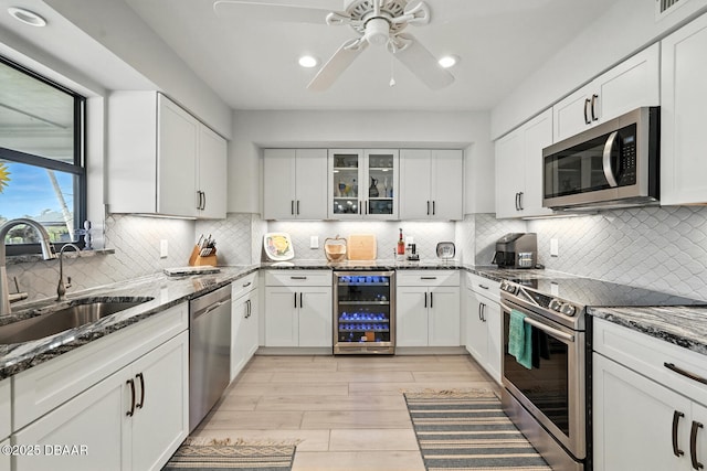 453 Palm Ave, Ormond Beach, FL 32174 - kitchen featuring wine cooler, appliances with stainless steel finishes, a ceiling fan, white cabinetry, and dark stone counters