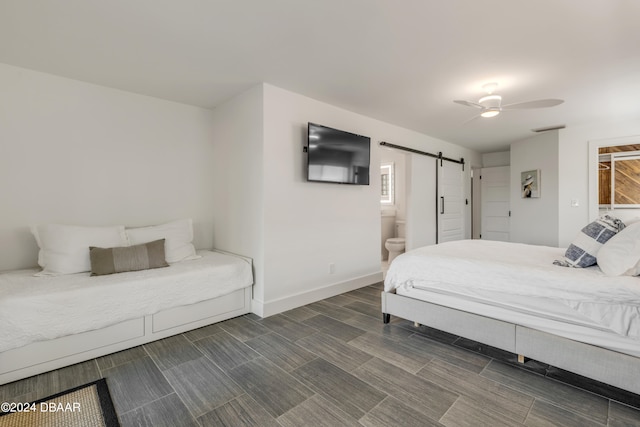 bedroom with a barn door, ensuite bath, and ceiling fan