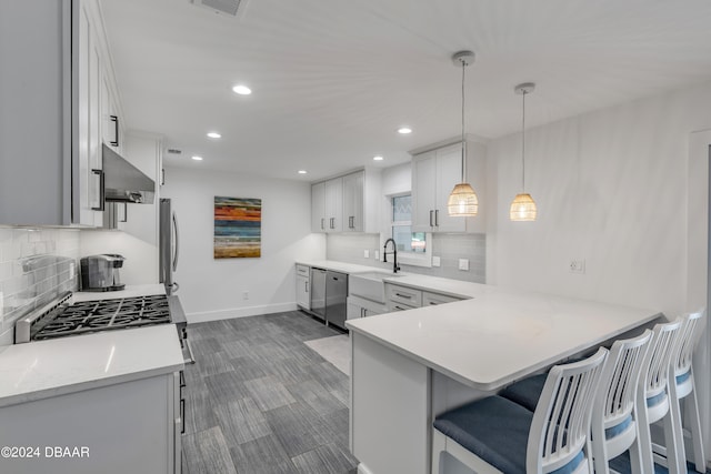 kitchen with white cabinets, sink, hanging light fixtures, kitchen peninsula, and stainless steel appliances