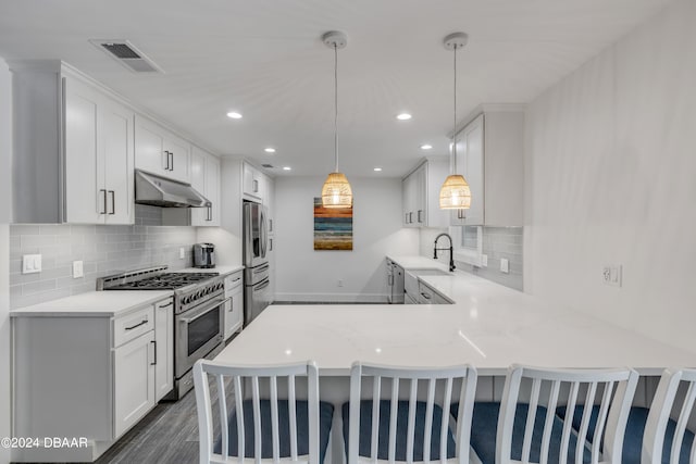 kitchen featuring sink, stainless steel appliances, kitchen peninsula, decorative light fixtures, and white cabinets