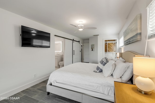 bedroom featuring a barn door, ceiling fan, and ensuite bathroom