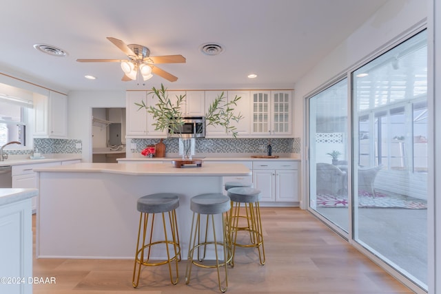 kitchen featuring backsplash, white cabinetry, light wood-type flooring, and appliances with stainless steel finishes