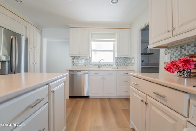 kitchen with white cabinets, sink, decorative backsplash, light hardwood / wood-style floors, and stainless steel appliances