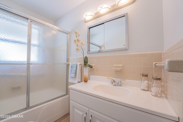 bathroom with vanity, bath / shower combo with glass door, and tile walls