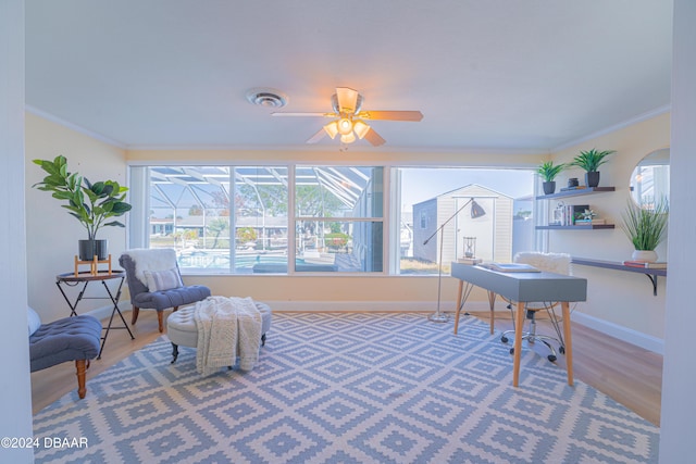 living area with crown molding, hardwood / wood-style floors, and ceiling fan